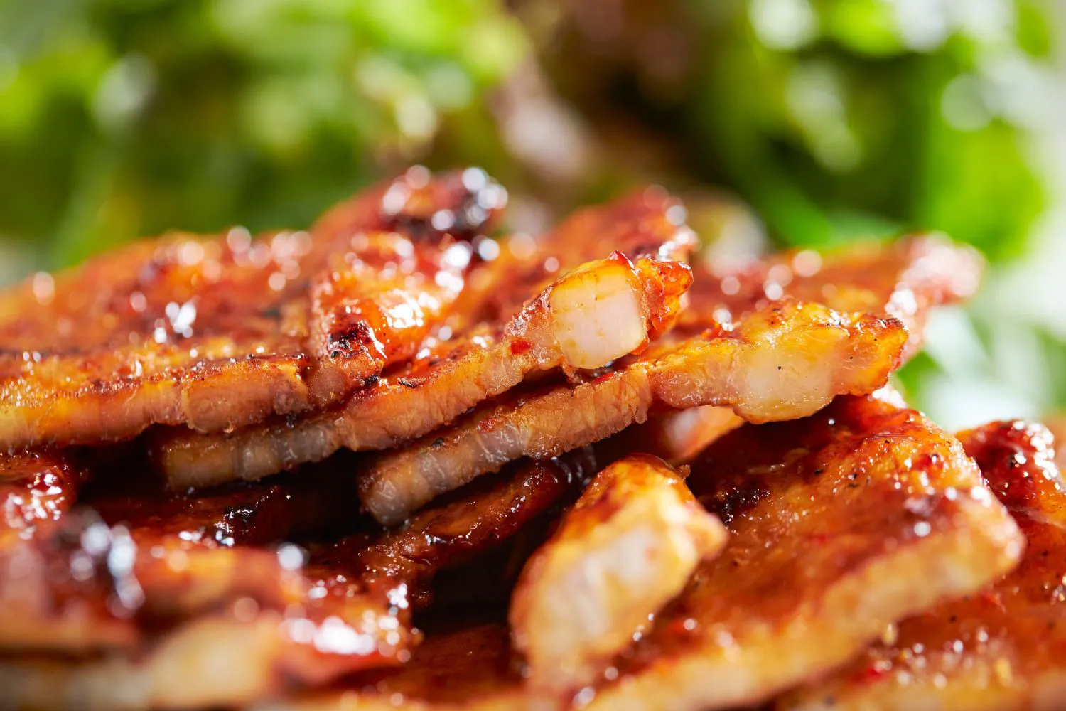 Close-up shot of glossy grilled marinated pork belly stacked together at Feast Utopia Clackamas, an Asian Fusion Restaurant in Clackamas