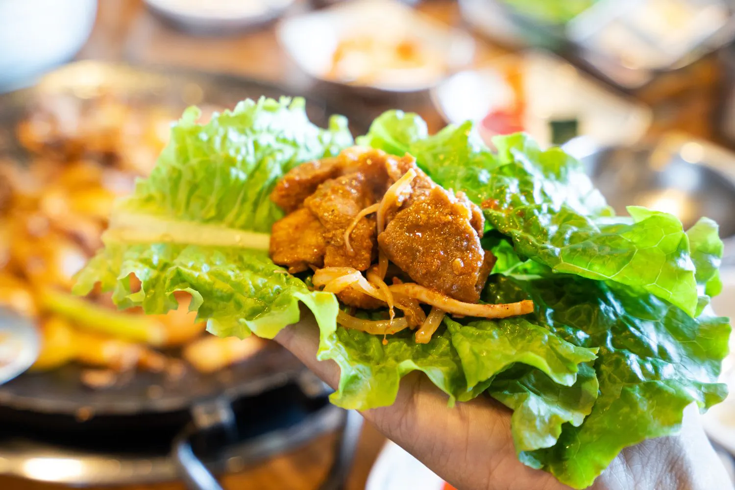 Grilled marinated pork wrapped in fresh lettuce leaf with shredded onion at Feast Utopia Clackamas, an Asian Fusion Restaurant in Clackamas