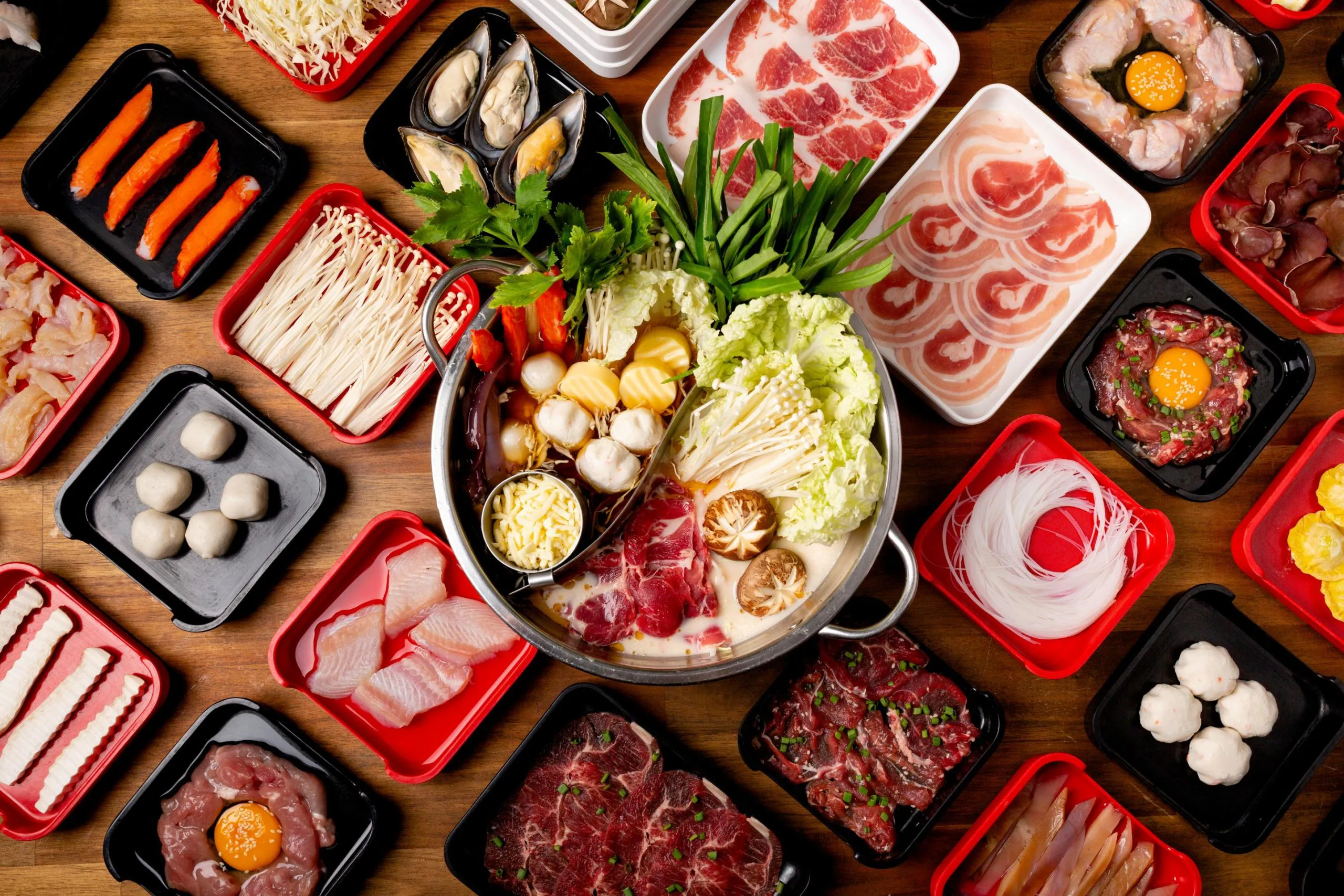 Top-down full hot pot raw ingredient spread with assorted meats, seafood, mushrooms and tofu at Feast Utopia Clackamas, an Asian Fusion Restaurant in Clackamas